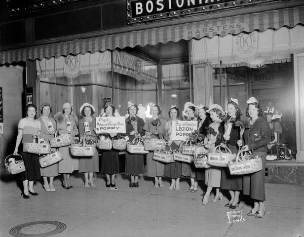 Group of Fanchon & Marco show girls with baskets of American Legion poppies in front of Karsten's, 22-24 North Carroll Street.