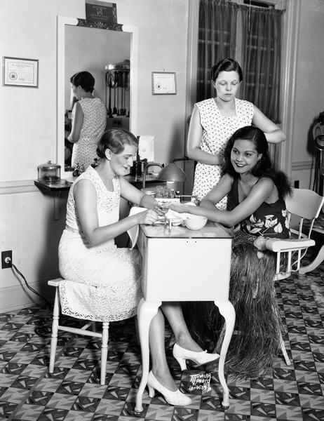 Ida Osthoff, manager of the Grace Beauty Shop, 130 State Street, does a manicure, and Pearl Holman gives a finger wave to Reri (Anne Chevalier). Chevalier was the Tahitian star of the Fanchon and Marco "Tahiti" show at the Orpheum Theatre.