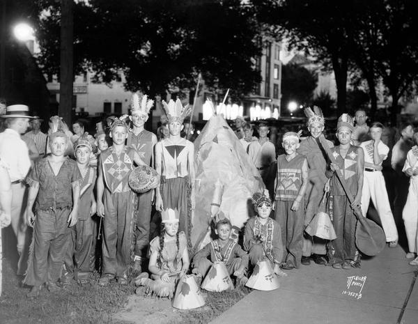 Group portrait of children from the South Side Franklin playground dressed as Indians surrounding a small tipi (teepee) prior to the Lantern Parade.