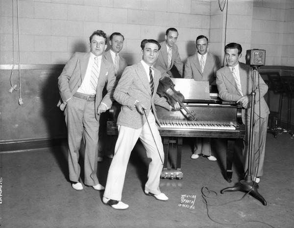 Anthony "Tony" Salerno's Gypsy Melodians posing at WIBA studios. Tony is leaning against the piano with his violin. Other Melodians are Otto Heinz, piano; Ben Ehr, sax and clarinet; Earl Barnes, trombone; Erwin Krueger, drums; and William Kraft, cornet.