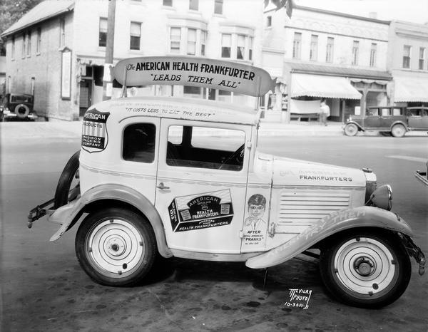 Austin automobile parked on the 300 block of W. Johnson Street (?),with  advertising "American Health Frankfurter -- leads them all," and "American Brand Products, Madison Packing Co." Madison Packing Co., Oswald Neesvig, Pres., 307 W. Johnson Street.