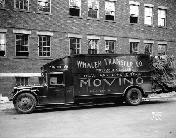 A Whalen Transfer Company moving van, parked in front of a large brick building, is filled to the brim with items to be stored or moved.