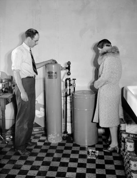 C.E. Bates Plumbing Company salesman showing the Trupar water softener to a customer, 1425 Regent Street.