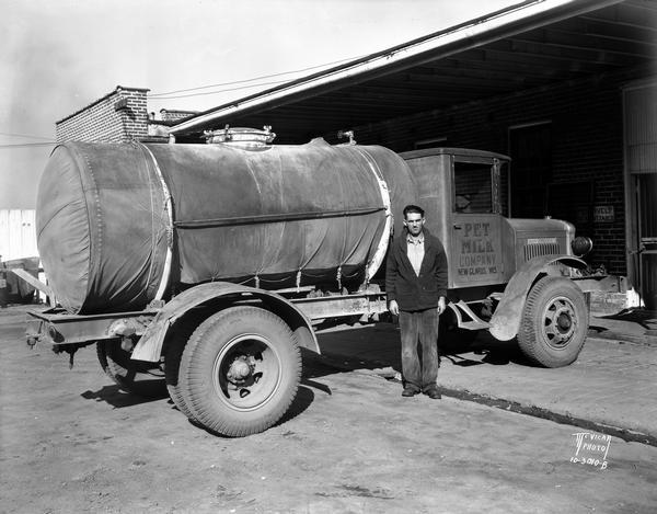 A man is standing outdoors next to a Pet Milk Company tanker truck. Note on negative enveloper: "Tires gone 52,000 miles."