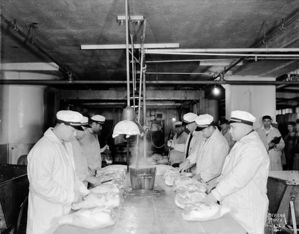Oscar Mayer workers inspecting hams at a work table.