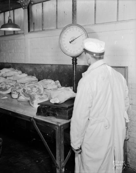 A man weighing hams on a scale at Oscar Mayer.