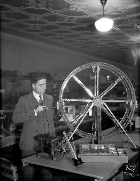 A man builds a Ferris wheel with an Erector set at Wolff-Kubly & Hirsig Company, located at 17 S. Pinckney Street.