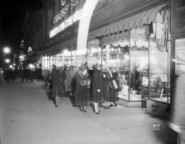 Women walk past a display window featuring Sherwin Williams paint, at Baron Brothers Department Store, located at 12-18 W. Mifflin Street.