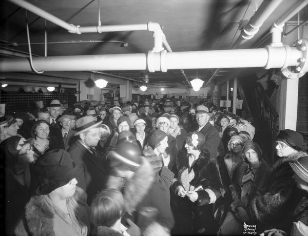 A crowd of people is waiting in the basement of the Baron Brothers Department Store for a drawing sponsored by Sherwin Williams Paint Company, located at 12-18 W. Mifflin Street.