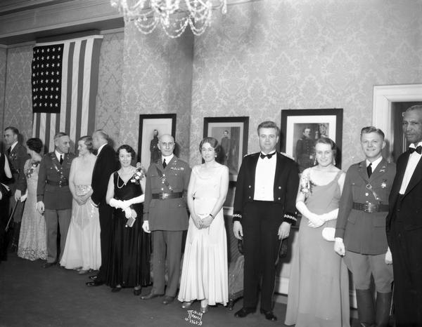 Attendees in formal wear are standing in a military ball receiving line,  from right to left: Sam Pierce, Arnold H. Dammen, Helga Gundersen, Ralph M. Immell, Dorothy Irwin, Colonel and Mrs. A.V.P. Anderson, Dean Scott H. Goodnight, Jane Bloodgood, Major and Mrs. Fox, and Fred Maytag.