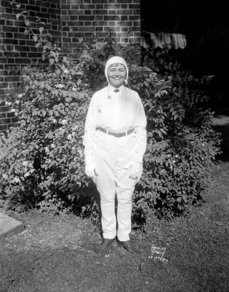 Portrait of Mary Wright (Mrs. H. Foster) Bain, who flew her own airplane from her home in Newark, N.J. to her University of Wisconsin reunion. She is posing outdoors dressed in flying clothes.