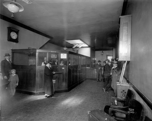 Interior of the First National Bank of Edgerton, with customers and tellers in cages.