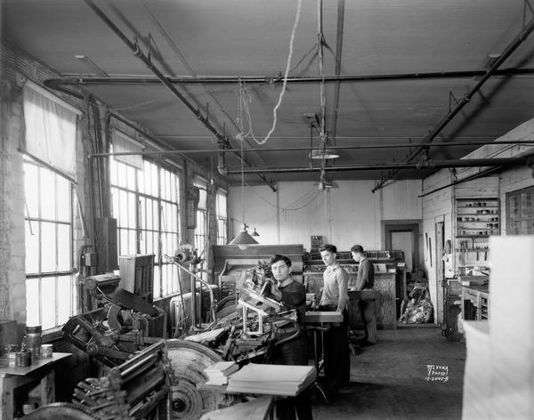 Interior of Feldman Paper Box Company printing department, 21-33 N. Charter Street, with three men at the machines.