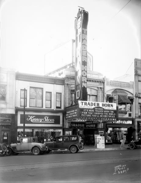View of the front of the Strand Theatre at 16 East Mifflin Street, advertising the film, "Trader Horn," flanked by Kinney Shoes, 14 East Mifflin Street, and Barton's, 18 East Mifflin Street.