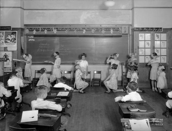 Twelve girls performing Japanese dance in front of classmates in a Dudgeon School classroom.