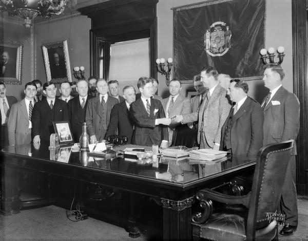 Governor Philip F. La Follette handing pen to Assemblyman Schmiege after signing old age pension bill.