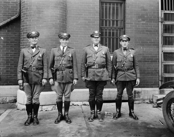 Group portrait of 4 motor police officers in uniform.