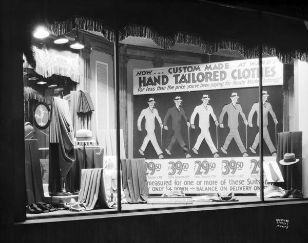 Montgomery Ward window display featuring men's suit fabrics and accessories, and a sign advertising, "Now Custom Made Hand Tailored Men's Suits." The store was at 100 North Hamilton Street.
