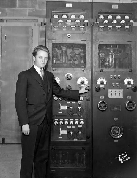 Everett Marshall, engineer, standing at the control panel of the radio station, WIBA.