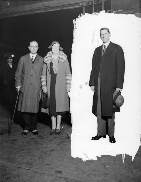 United States Secretary of the Interior Ray Lyman Wilbur and his wife at the Northwest railroad station, with an unidentified man isolated by a masked background.