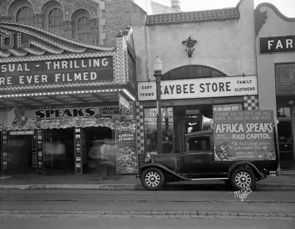 A truck with sign advertising the movie, "Africa Speaks" is parked in front of the Kaybee Store, next to the Capitol Theatre, 209 State Street where the movie is playing.