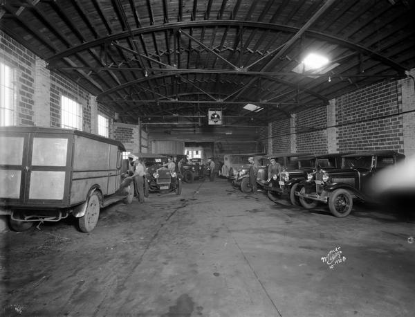 Vehicles parked inside the cavernous Royal Auto Body shop are attended to by workers.