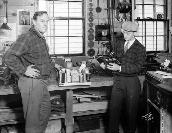 Repairmen at Kidder's Radio repair department posing next to their workbench.