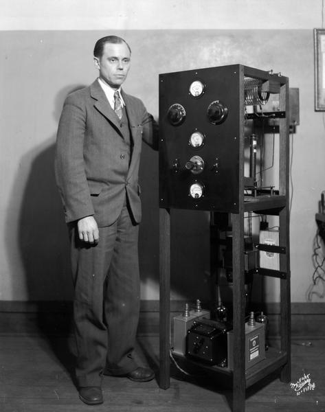 Walter T. Butler stands beside a radio transmitter in his store, Butler Radio Service, 606 University Avenue.