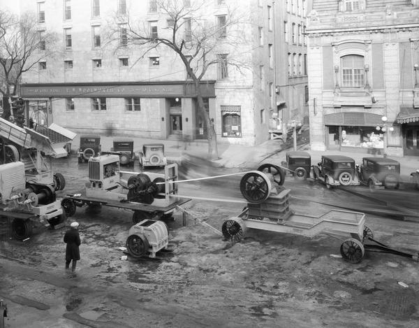 Elevated view of Wisconsin Foundry and Machine Co. road construction equipment, featuring a new portable rock crushing plant, being displayed at the Wisconsin Road Show on Monona Avenue. On the other side of the street is the F.W. Woolworth's (Pioneer Building) at 105 Monona Avenue. Included in the view are Marty Schwartz Cigars at 111 Monona Avenue and the Garrick Theatre, 113 Monona Avenue.
