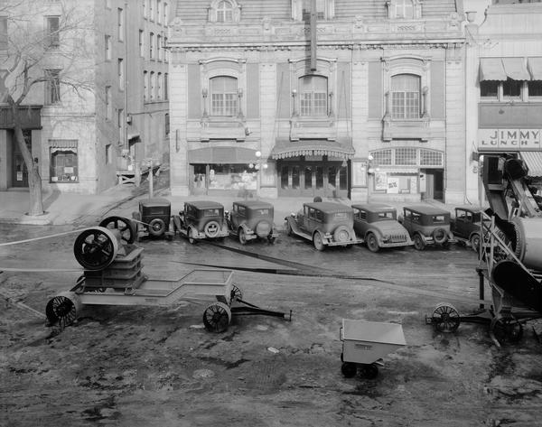 Elevated view of Wisconsin Foundry and Machine Co. road construction equipment, featuring a new portable rock crushing plant, on display at Wisconsin Road Show on Monona Avenue. On the other side of the avenue is the Pioneer Building, 105 Monona Avenue, Kehoe cigars, 111 Monona Avenue, the Garrick Theatre, 113 Monona Avenue, and the Jimmy Dodge Lunch-Billiards, 117 Monona Avenue.