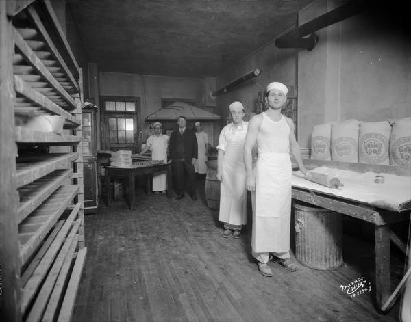 Five bakers standing in the kitchen of Mel-O-Cream Doughnut Shop, 548 W. Washington Avenue, with large bags of Golden Loaf flour.