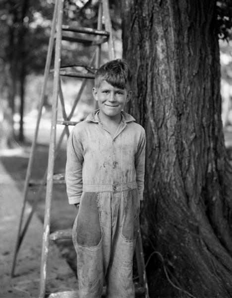 Paul Vilbrandt, age 10, standing by a tree and ladder at the 1200 block of West Dayton Street, hoping to break the tree sitting record of Jimmie Clemons of Racine. He and Herbert Van Abel, age 12, placed first and set a new world's record.