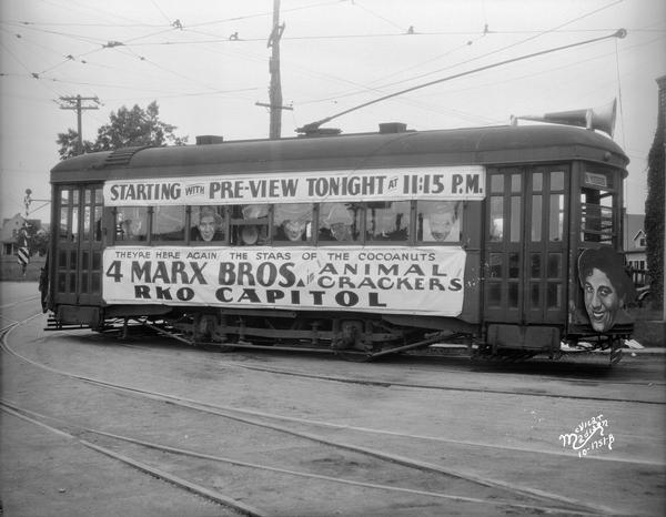 Banners and caricatures of the Marx Brothers adorn a streetcar advertising the film "Animal Crackers" at the RKO Capitol Theatre.