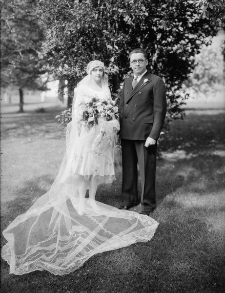 Outdoor wedding portrait of Don Kennedy & Eleanor Rusch, set off by Eleanor's long veil and large flower bouquet.