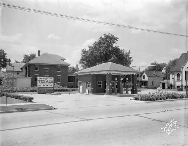 View from street towards the Texaco service station, with three gasoline pumps.