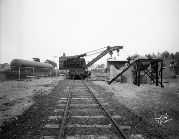 A Chicago & North Western Railroad Bucyrus crane installing a large tank at a Carbide & Carbon Chemicals Company Pyrofax plant, at 130 Fair Oaks Avenue.