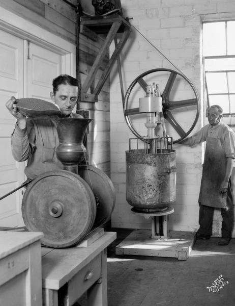Two men operate pulverizing and mixing machinery at the Floralo Incense Company, located at 1212 Regent Street.