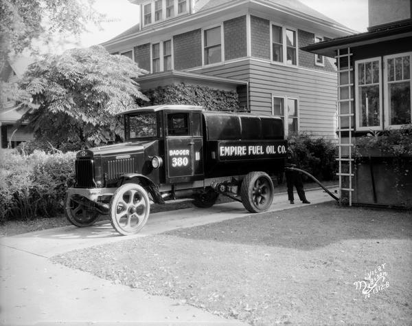 An Empire Fuel Company worker delivers fuel to a house at 1721 Regent Street through a hose attached to a company truck.