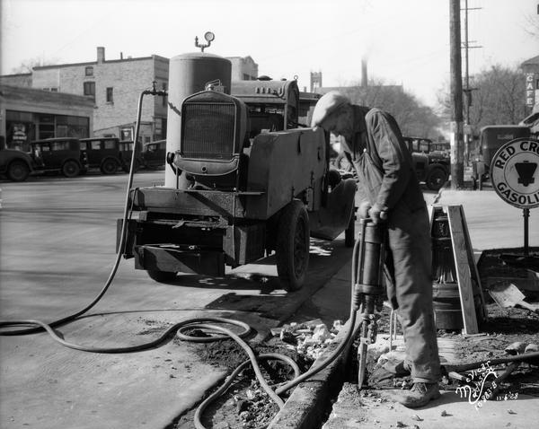 A worker is using an air hammer with compressor truck to do work on the road in the 800 block of University Avenue, looking west. Wisconsin Foundry & Machine Co.