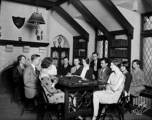 Group of men and women students of the executive council are sitting around a table in the study of the Calvary Lutheran University Church, located at 713 State Street.