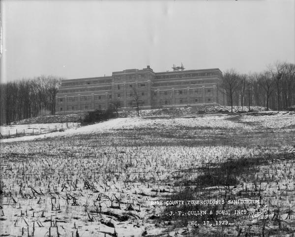 View up hill towards the construction site of the Dane County Tuberculosis Sanatorium, which is nearing completion. Snow is on the ground. The building is located at 1202 Northport Drive. J.P. Cullen, Contractor.