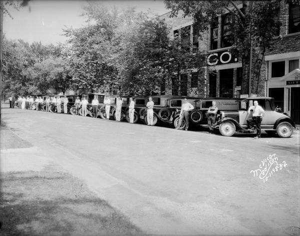 Fleet of 19 3-F Steam Laundry trucks and one automobile, with drivers standing beside their vehicles in front of office and plant at 731-747 East Dayton Street.