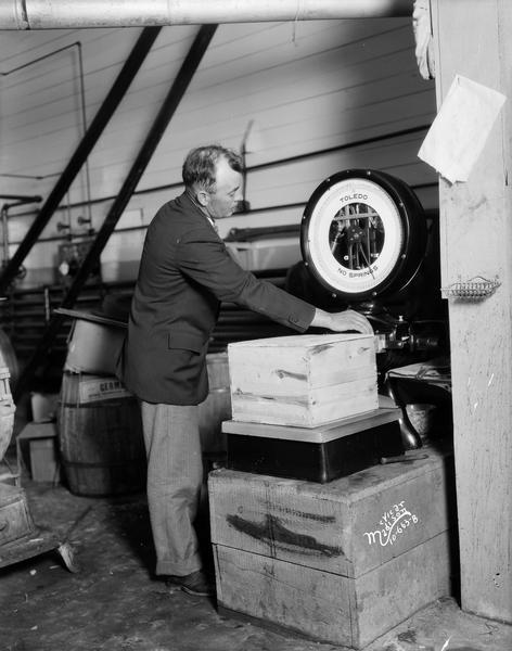 Man weighing a box on a Toledo scale at the Belmont Creamery.