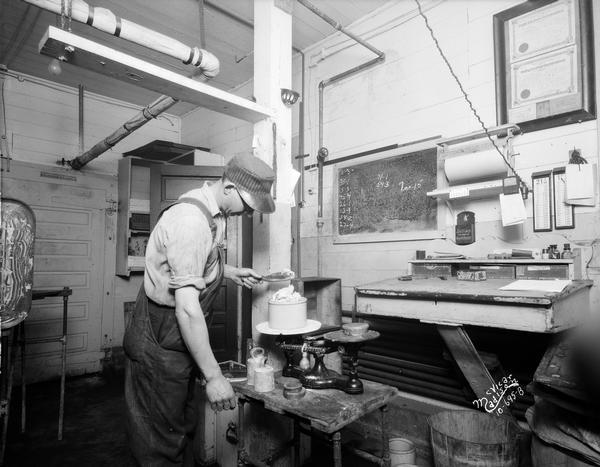 Man using an old scale at the H.M. Zander Creamery.