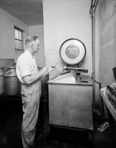 Man using a Toledo scale at the Mernick Dairy.