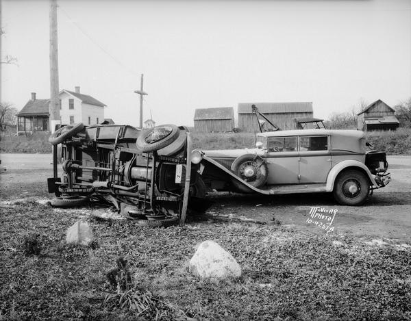 Frank Lloyd Wright's 1929 L-29 Cord Phaeton automobile and an overturned Choles Floral Company delivery truck, driven by Frost Choles, at an accident scene at Lakeview north of Oregon, corner of Lakeview Road Highway B and Oregon Road Highway MM. The view also contains the McAvoy farm house and farm buildings in the background.