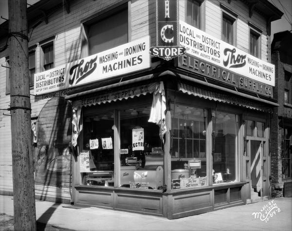 Front view of the Electrical Supply Company, located at 202 East Washington Avenue. There is a sign on the outside for "Thor washing and ironing machines."