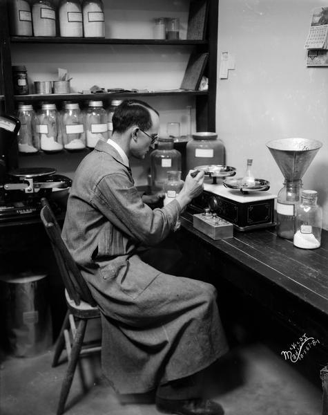 A man is measuring chemicals on an old scale in Ricketts laboratory at the Agriculture Chemistry Building, on the University of Wisconsin campus.