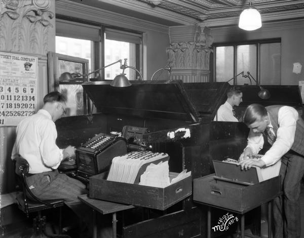 Three men in the Bookkeeping Department, Bank of Wisconsin, located at 1 West Main Street.