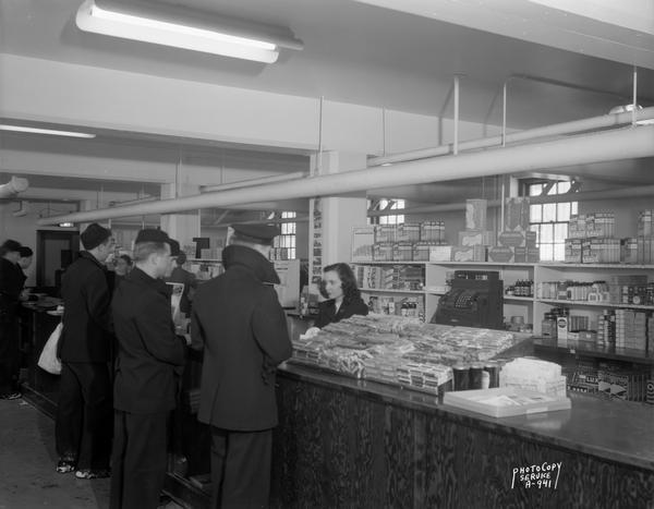 Female clerk selling items to Naval trainees at the U.S. Naval Training School (Radio) ship's store. The store was located in a University of Wisconsin dormitory.